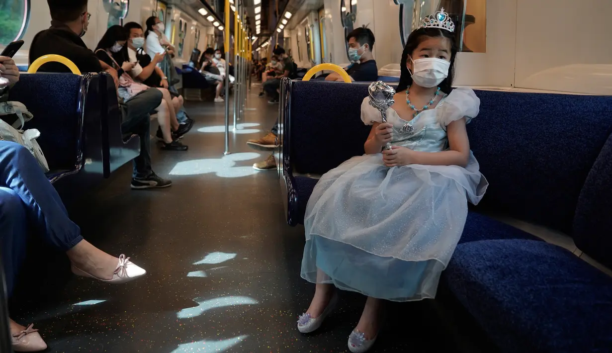 Seorang pengunjung yang mengenakan masker menaiki kereta menuju Hong Kong Disneyland pada Jumat (25/9/2020). Setelah dibuka dan tutup kembali, Disneyland Hong Kong dibuka kembali untuk wisatawan. (AP Photo/Kin Cheung)