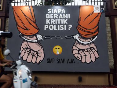 Warga melintas di depan mural berisi kritik terhadap kinerja polisi di Lapangan Bhayangkara Mabes Polri, Jakarta, Minggu (31/10/2021). Sejumlah mural berisi kritik terhadap polisi dipamerkan usai mengikuti ajang Mural Festival 2021 Piala Kapolri 2021. (Liputan6.com/Helmi Fithriansyah)