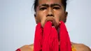 Penganut kuil Loem Hu Thai Su manusukkan benang ke pipinya hingga keluar melalui mulut saat festival vegetarian tahunan di Phuket, Thailand, Jumat (12/10). Setiap peserta harus rela wajahnya ditusuk dengan berbagai benda tajam. (Jewel Samad/AFP)