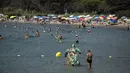 Para pengunjung menikmati hari yang panas di bawah sinar matahari pantai Bormes-les-Mimosas, Prancis, Selasa (11/8/2020). Cuaca panas diperkirakan akan berlangsung selama beberapa hari di seluruh negeri. (AP Photo/Daniel Cole)