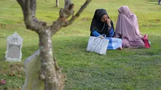 Dua perempuan Aceh berdoa di pemakaman massal Ulhee Lheue, Banda Aceh, Sabtu (26/12/2015).  Doa tersebut untuk keluarga mereka yang terkena bencana Tsunami pada 26 Desember 2014. (AFP Photo/ Chaideer Mahyuddin)
