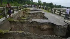 Warga India berkumpul melihat sebuah jembatan yang hancur akibat hujan deras di Desa Toribari, pinggiran Siliguri, Kamis (21/7). Hujan deras yang terus menerus turun di India dalam 48 jam terakhir menyebabkan banjir dan tanah longsor. (DIPTENDU Dutta/AFP)