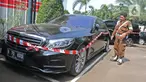 Petugas mengamati mobil mewah milik tersangka Jiwasraya yang terparkir di Kejaksaan Agung, Kamis (16/1/2020). Penyidik Kejagung menyita sejumlah kendaraan dari tersangka kasus dugaan korupsi Jiwasraya berupa enam mobil berbagai merk dan satu motor Harley Davidson. (Liputan6.com/Herman Zakharia)