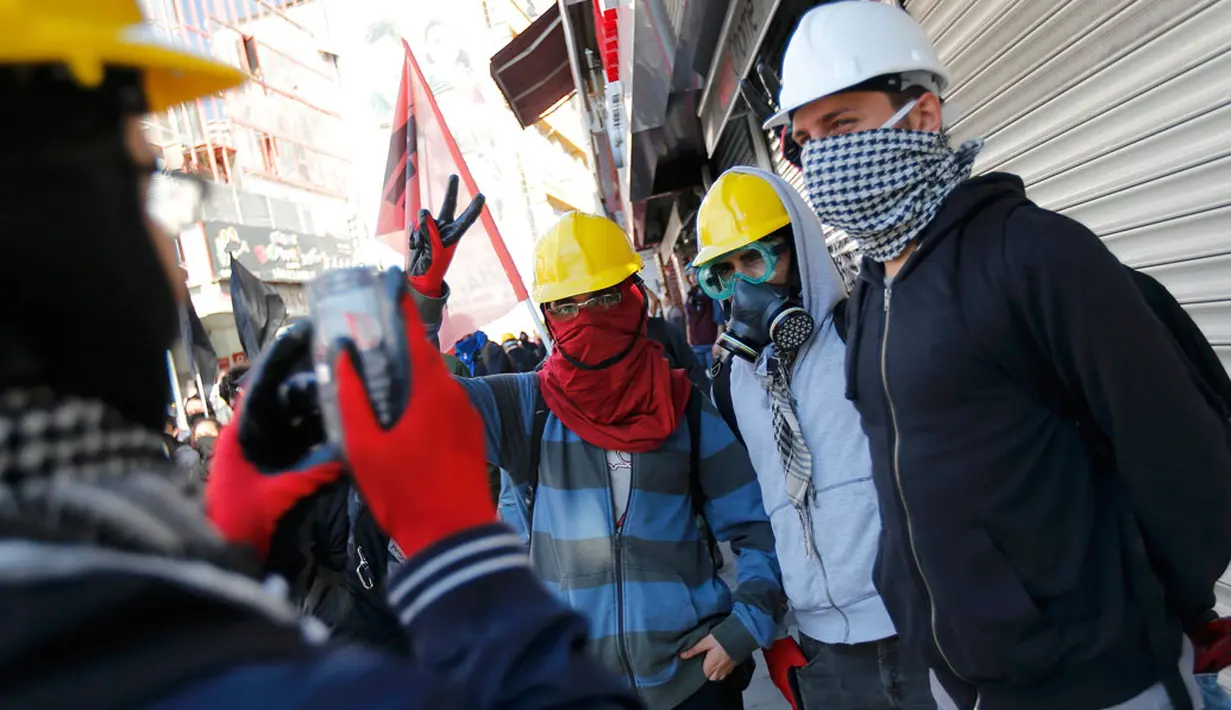 Kericuhan yang terjadi saat perayaan Hari Buruh Sedunia di Istanbul, Turki (1/5/2014) tidak menyurutkan semangat beberapa pengunjuk rasa untuk berpose bersama mengabadikan moment berharga. (REUTERS/Murad Sezer)