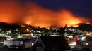 Langit memerah akibat kebakaran yang melanda kawasan Dichato Chili, Senin (30/1). Ketika kebakaran melanda kota Santa Olga pada Kamis malam, menewaskan 10 orang dan menghanguskan lebih dari 1.000 bangunan. (AP Photo / Esteban Felix)
