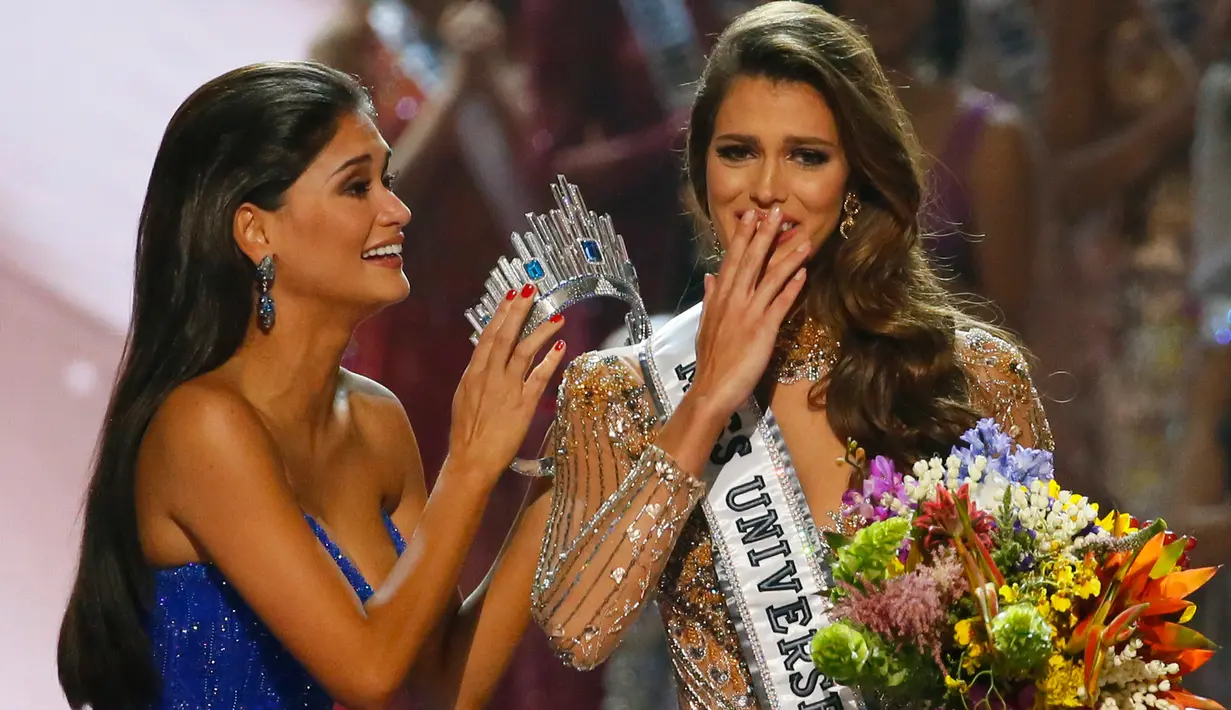 Miss Universe 2015, Pia Wurtzbach (kiri) bersiap memasangkan mahkota Miss Universe kepada Miss Prancis, Iris Mittenaere di Mall of Asia Arena, Manila, Filipina, Senin (30/1). Iris Mittenaere dinobatkan menjadi Miss Universe 2016. (AP Photo/Bullit Marquez)