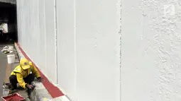 Pasukan Kuning mengecat dinding Underpass Kebayoran Baru, Jakarta Selatan, Kamis (1/2). Pasukan Kuning berada di bawah naungan Dinas Bina Marga Pemerintahan Provinsi DKI Jakarta. (Liputan6.com/Immanuel Antonius)