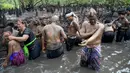 Orang-orang mengambil bagian dalam tradisi mandi lumpur yang dikenal sebagai Mebuug-buugan di Desa Kedonganan, Bali, 4 Maret 2022. Mebuug-buugan diadakan sehari setelah Nyepi yang bertujuan untuk menetralkan sifat buruk. (SONY TUMBELAKA/AFP)