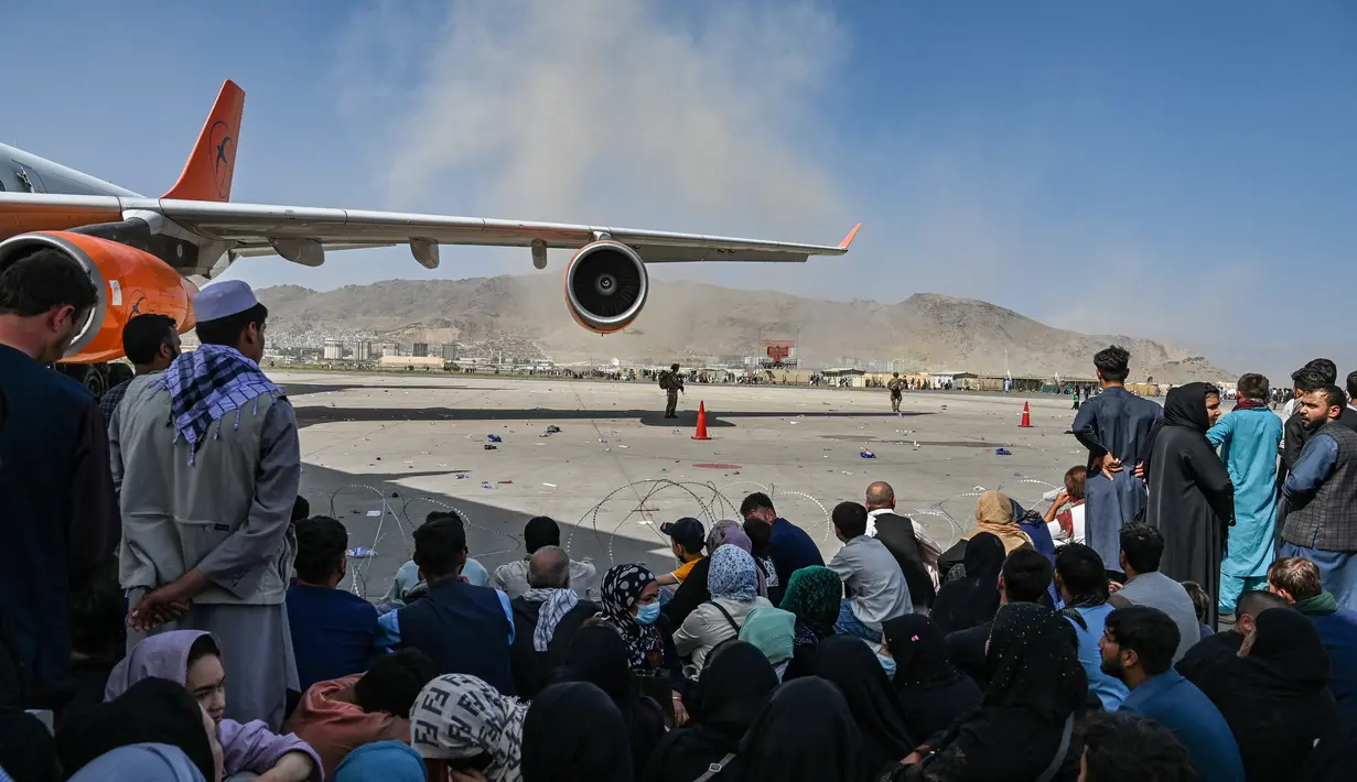 Orang-orang Afghanistan duduk ketika mereka menunggu untuk meninggalkan bandara Kabul (16/8/2021). Pemerintah Afghanistan yang didukung Amerika Serikat (AS) selama 20 tahun terakhir ini telah runtuh setelah Taliban merebut banyak wilayah. (AFP/Wakil Kohsar)