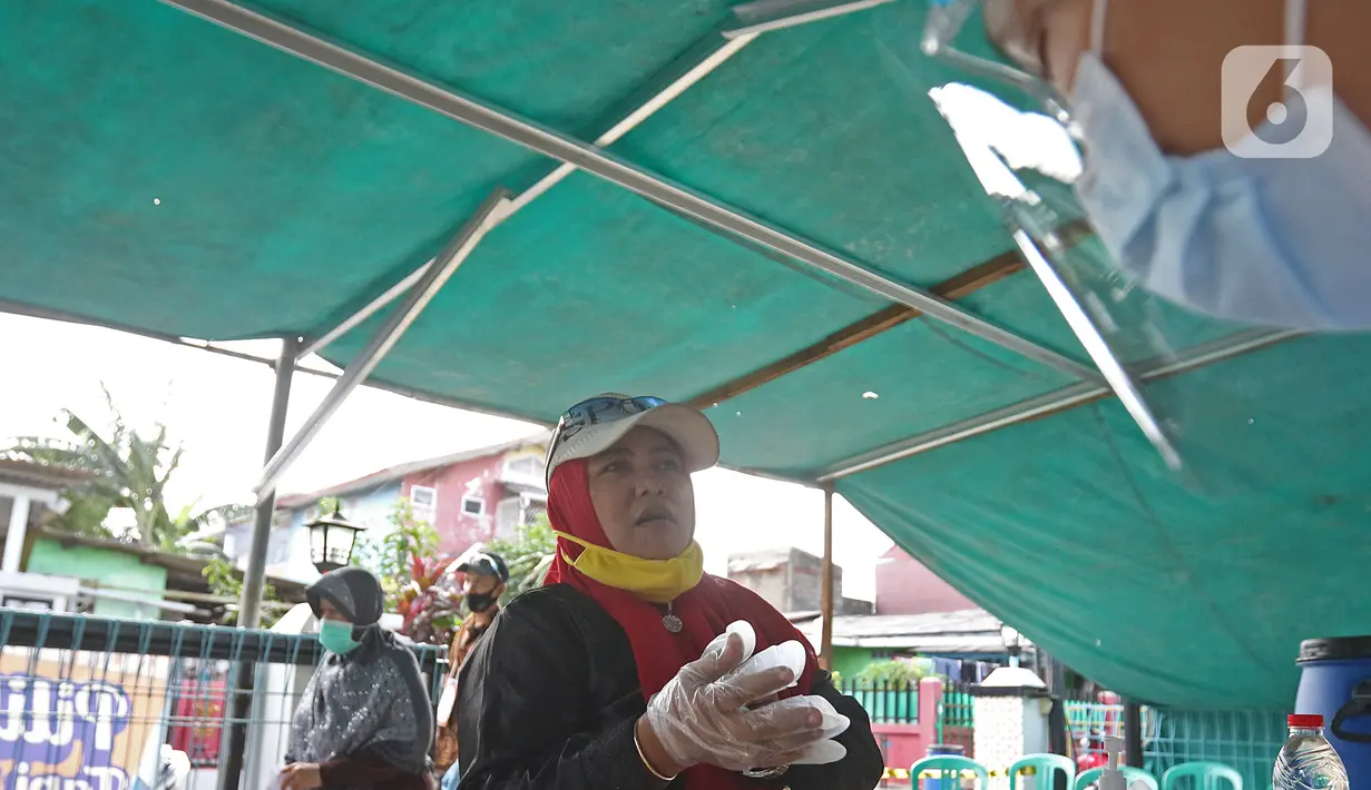 Warga mengenakan sarung tangan plastik sebelum menggunakan hak pilihnya dalam Pilkada Depok di TPS 56, Mekarjaya, Depok, Rabu (9/12/2020). TPS 56 menggunakan tema kesehatan untuk menarik warga menggunakan hak pilih dan mengingatkan protokol kesehatan COVID-19. (Liputan6.com/Herman Zakharia)