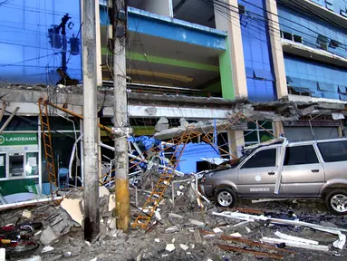 Sebuah mobil tertimpa puing bangunan yang runtuh akibat gempa 6,5 SR yang melanda Surigao City, Pulau Mindanao, Filipina (11/2). Gempa yang terjadi di saat warga sedang lelap tidur itu menghancurkan banyak bangunan, dan bandara. (AFP/Erwin Mascarinas)