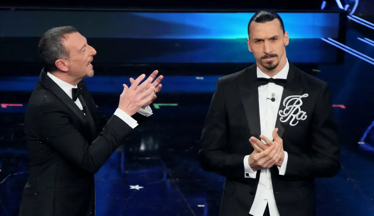 Striker AC Milan, Zlatan Ibrahimovic (kanan) dan presenter televisi Italia Amadeus tampil pada malam pembukaan festival musik San Remo di San Remo, Selasa (2/3/2021). Ibrahimovic yang sedang cedera melakukan debutnya sebagai pembawa acara di festival musik tersebut. (Marco RAVAGLI/AFP)