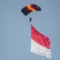 Penerjun payung membawa bendera Merah Putih saat perayaan HUT ke-73 Bhayangkara di Monas, Jakarta, Rabu (10/7/2019). Sebanyak 22 penerjun payung dari TNI dan Polri ikut menyemarakkan HUT ke-73 Bhayangkara. (Liputan6.com/Faizal Fanani)