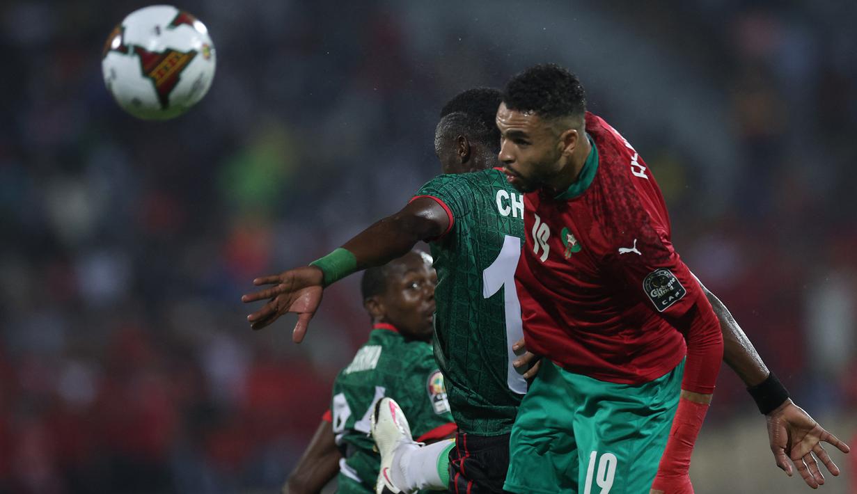 Penyerang Maroko Youssef En-Nesyri menyundul bola dibayangi pemain Malawi pada babak 16 besar Piala Afrika 2021 di Ahmadou Ahidjo Stadium, Yaounde, Rabu (26/1/2022) dini hari WIB. Achraf Hakimi menjadi penentu kemenangan Maroko atas Malawi, 2-1. (Kenzo Tribouillard/AFP)