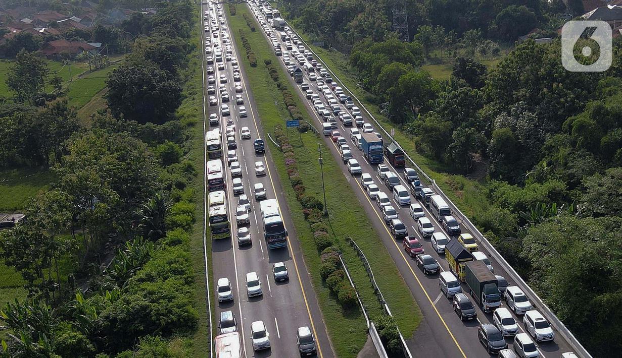 Foto udara memperlihatkan antrean kendaraan pemudik yang mengurangi laju kendaraannya saat melintasi jalan tol Palimanan-Kanci (Palikanci) KM 192, Cirebon, Jawa Barat, Minggu (7/4/2024). (Liputan6.com/Herman Zakharia)