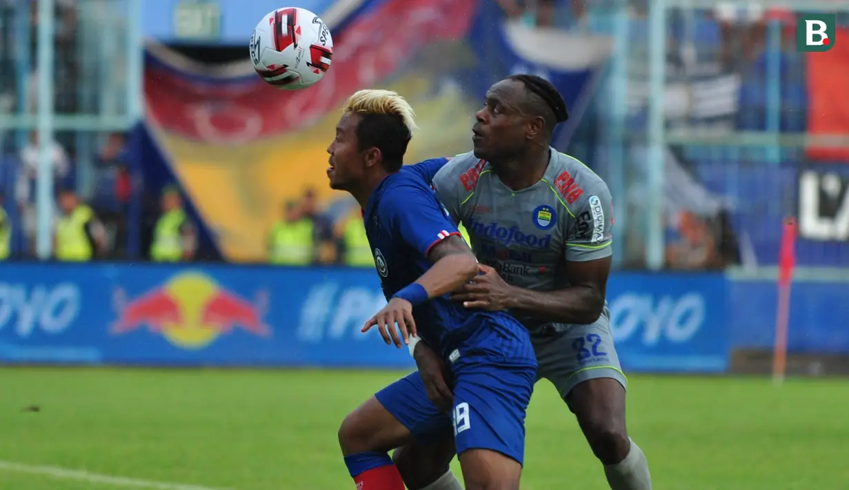 Duel sengit penyerang Arema FC, Kushedya Hari Yudo (biru), dan bek Persib Bandung, Victor Igbonefo, saat kedua tim bertemu di laga pekan kedua Shoppe Liga 1 2020 di Stadion Kanjuruhan, Minggu (8/3/2020). (Bola.com/Iwan Setiawan)