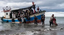 Nelayan membantu mengevakuasi pengungsi etnis Rohingya setibanya di pesisir pantai Lancok, di Kabupaten Aceh Utara, Kamis (25/6/2020). Nelayan Indonesia menemukan hampir 100 orang etnis Rohingya, termasuk 30 orang anak-anak terdampar di tengah laut dengan kondisi kapal rusak. (AP Photo/Zik Maulana)