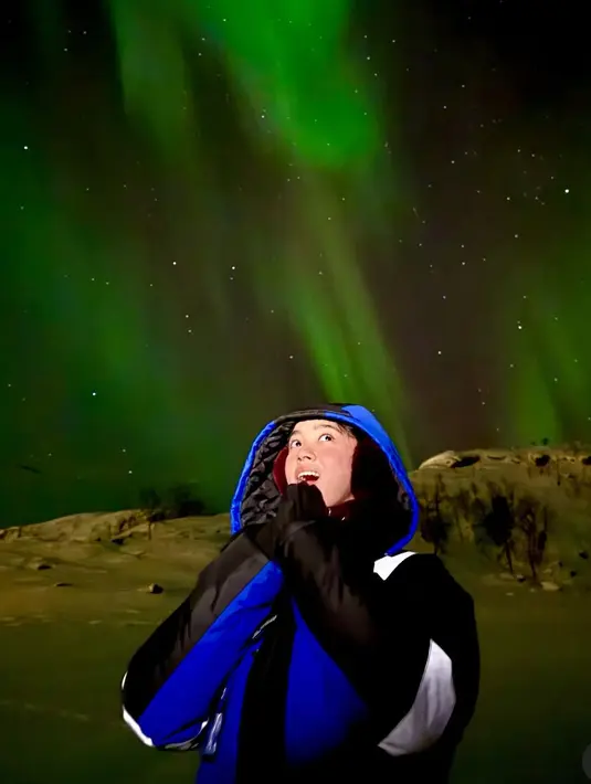 Lyodra juga menikmati aurora di Norway dengan mengenakan jaket biru dan hitam. Tampak wajahnya pun memerah karena dingin. [@lyodraofficial]