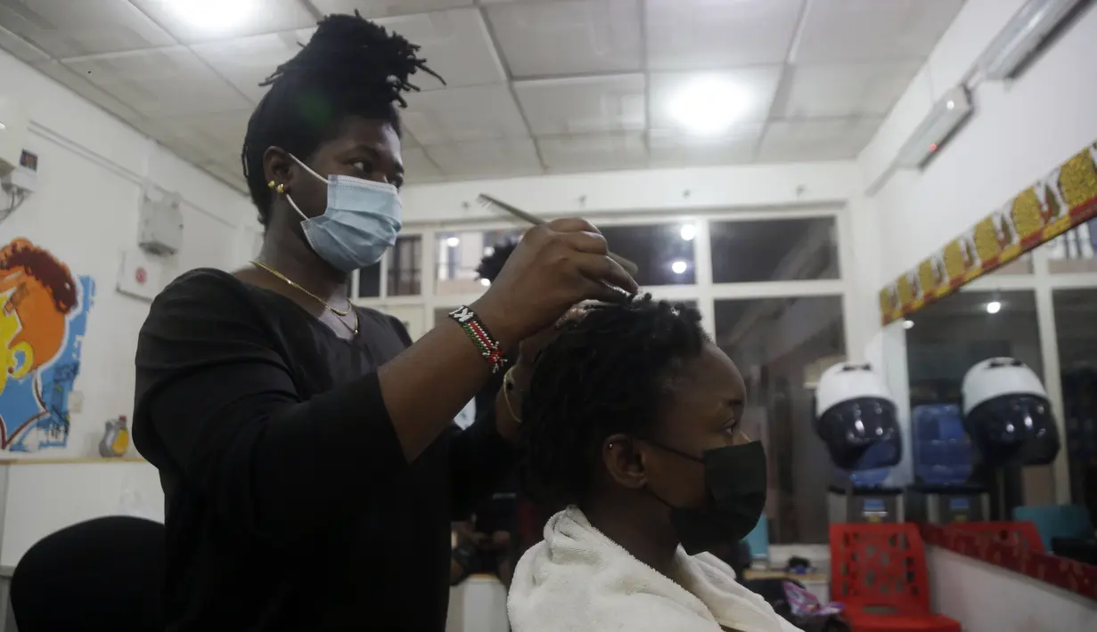 Penata rambut, memakai masker menata rambut pelanggan di dalam salon di Lagos, Nigeria, Rabu (26/5/2021). Salon tersebut menerapkan protokol kesehatan untuk para penata rambutnya saat melayani pelanggan untuk menghindari penyebaran virus Covid-19. (AP Photo/Sunday Alamba)