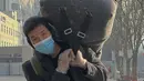 Seorang pekerja migran yang mengenakan masker dan sarung tangan membawa barang bawaannya saat tiba di Stasiun Kereta Api Barat di Beijing, Jumat (6/1/2023). China berupaya meminimalkan kemungkinan wabah COVID-19 yang lebih besar selama kesibukan perjalanan Tahun Baru Imlek bulan ini menyusul berakhirnya sebagian besar langkah-langkah pencegahan pandemi. (AP Photo/Wayne Zhang)