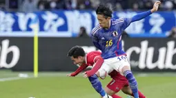 Pemain Jepang, Seiya Maikuma, berebut bola dengan pemain Thailand, Supachok Sarachat, pada laga uji coba di Stadion Nasional Jepang, Tokyo, Senin (1/1/2023). (AP Photo/Shuji Kajiyama)