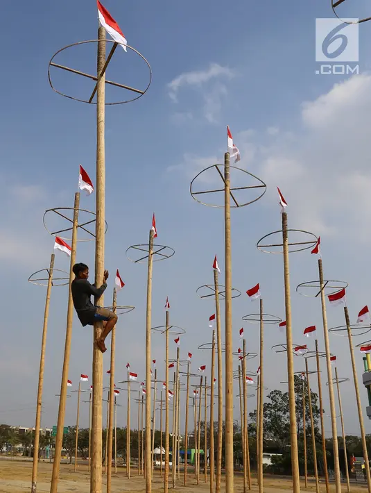 Pekerja memasang bendera Merah Putih pada pohon pinang untuk acara panjat pinang kolosal di kawasan Ancol, Jakarta, Kamis (15/8/2019). Ancol Taman Impian memasang sebanyak 174 batang pohon pinang untuk meriahkan Hari Kemerdekaan dengan tema " Pesta Manusia Merdeka". (Liputan6.com/Herman Zakharia)