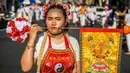 Seorang wanita menusuk pipinya dengan besi  saat mengikuti prosesi perayaan Festival Vegetarian tahunan di Phuket, Thailand, Kamis (3/10/2019). Festival ini biasanya berlangsung selama 9 hari di akhir September sampai Oktober. (AFP Photo/Mladen Antonov)