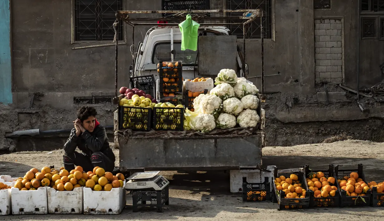 Pedagang kaki lima memajang sayuran dan buah-buahan untuk dijual di kota Raqa, bekas ibu kota ISIS, di Suriah utara pada 20 Desember 2020. Raqqa menjadi saksi terusirnya anggota kelompok ekstremis oleh Pasukan Demokratik Suriah pada Oktober 2017 lalu. (Photo by Delil SOULEIMAN / AFP)