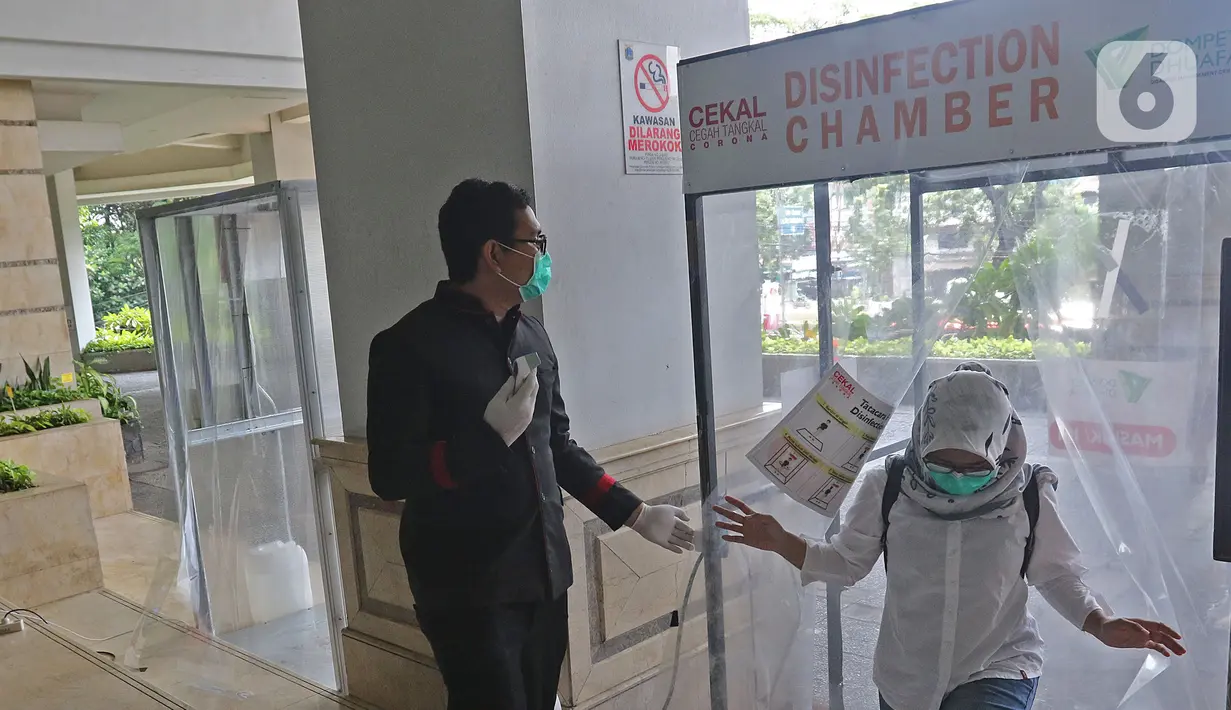 Petugas Medis keluar dari bilik disinfektan di Hotel Grand Cempaka , Jakarta, Sabtu (28/3/2020). Hotel ini disediakan oleh Pemprov DKI sebagai tempat istirahat 343 tenaga medis, 28 di antaranya dokter, yang menangani kasus Corona Covid-19 di ibu kota. (Liputan6.com/Herman Zakharia)