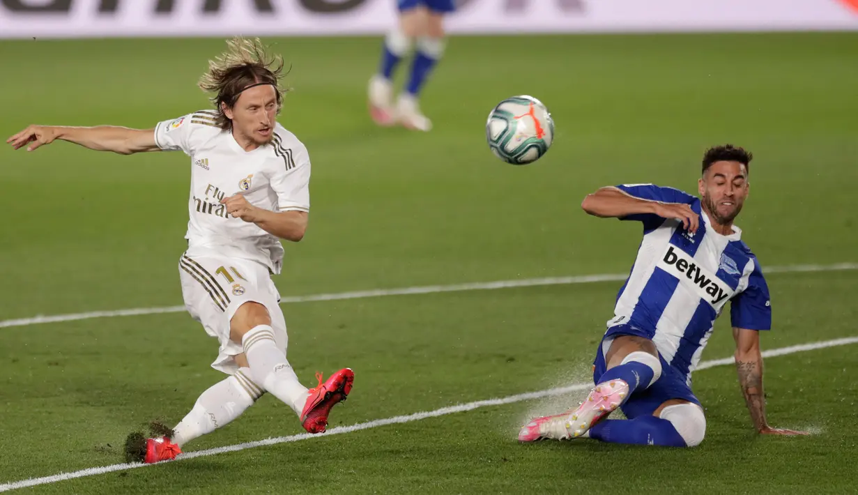 Gelandang Real Madrid Luka Modric melepaskan tembakan yang berusaha dihentikan pemain Alaves, Victor Camarasa pada lanjutan Liga Spanyol di stadion Alfredo di Stefano, Sabtu (11/7/2020). Real Madrid menang 2-0 lewat gol Karim Benzema dan Marco Asensio. (AP Photo/Bernat Armangue)