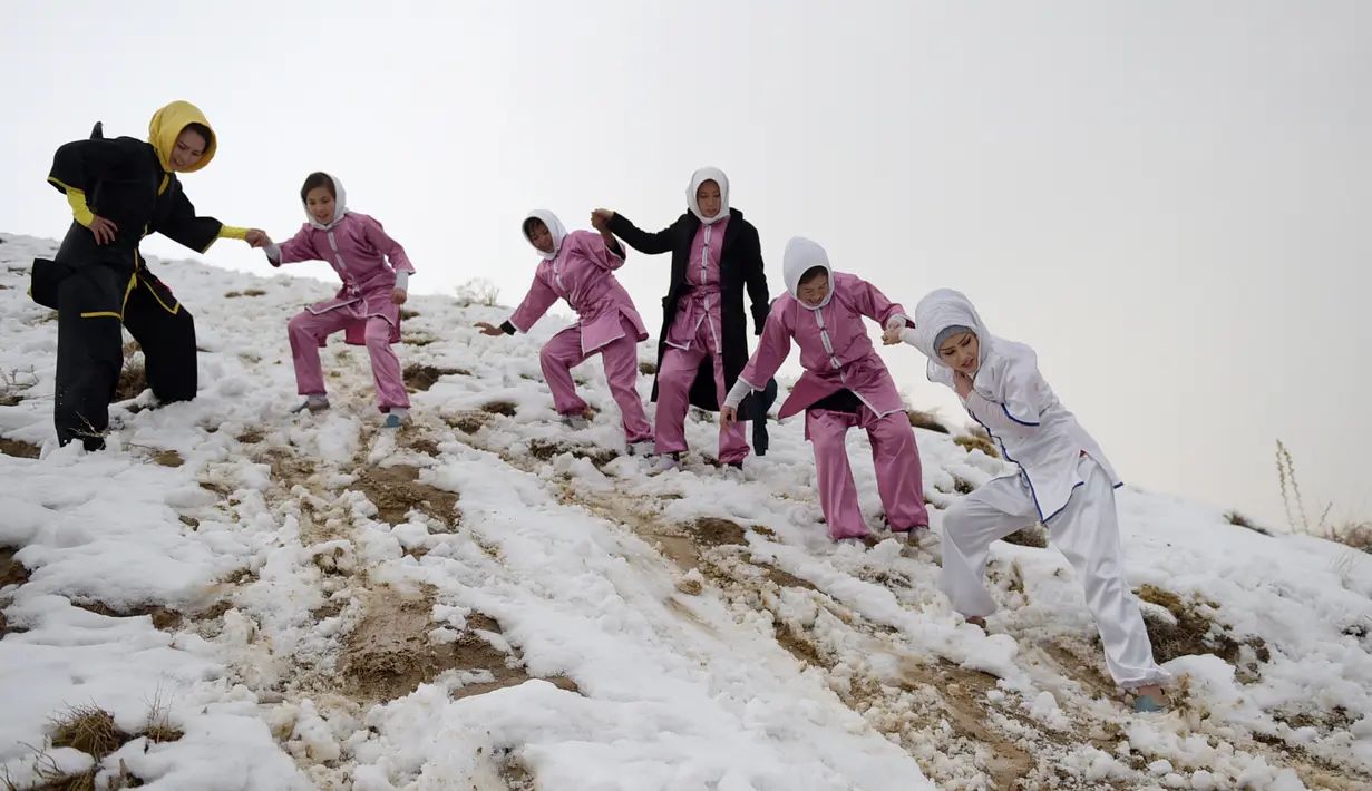 Sima Azimi (kiri) bersama para muridnya menuruni bukit Shahrak Haji Nabi, Kabul, setelah berlatih seni bela diri wushu, 29 Januari 2017. Sima Azimi tengah melatih 20 gadis Afghanistan berusia 14-20 tahun di sebuah klub Wushu di Kabul. (WAKIL KOHSAR/AFP)