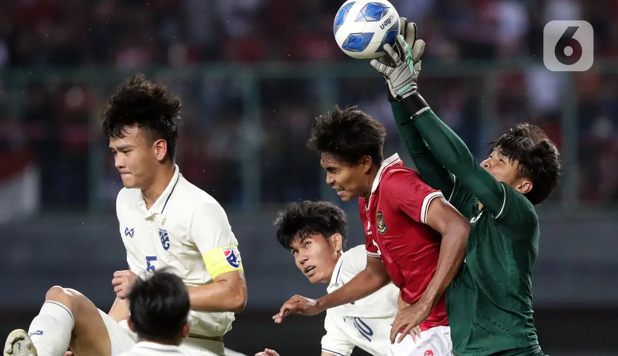 Pemain belakang Timnas Indonesia U-19, Ahmad Rusadi (kedua kanan) berebut bola atas dengan penjaga gawang Thailand U-19, Narongsak Naengwongsa pada lanjutan penyisihan grup A Piala AFF U-19 2022 di Stadion Patriot Candrabhaga, Bekasi, Jawa Barat, Rabu (6/7/2022). Laga kedua tim berlangsung imbang 0-0. (Liputan6.com/Helmi Fithriansyah)