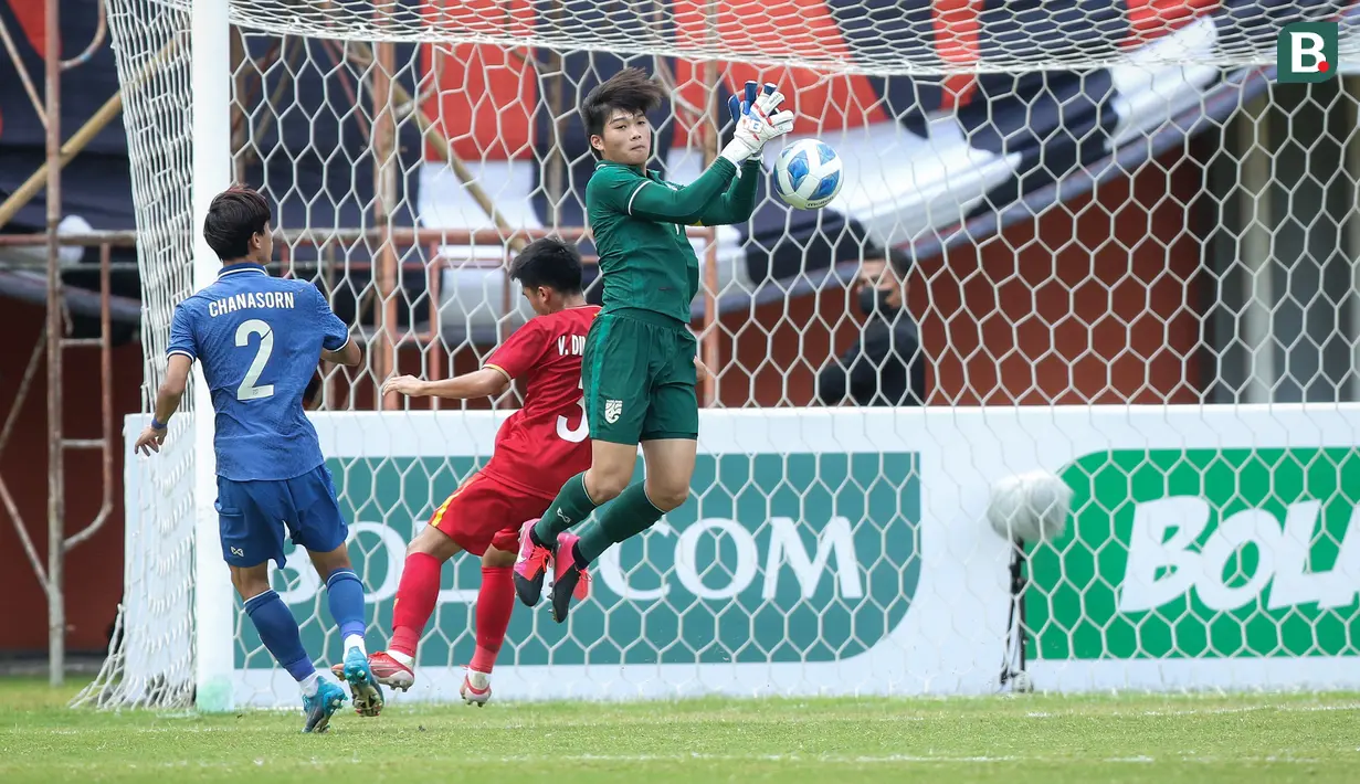 Kiper Thailand U-16, Tissanu Khuptanawin berusaha menghalau bola dari ancaman pemain Vietnam U-16, Vi Dinh Thuong dalam laga semifinal AFF U-16 2022 antara Thailand U-16 melawan Vietnam U-16 di Stadion Maguwoharjo, Sleman, Rabu (10/8/2022) sore WIB. (Bola.com/Bagaskara Lazuardi)