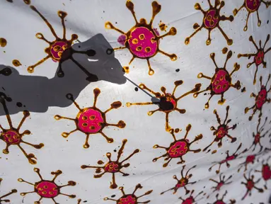Penyandang disabilitas menjemur kain batik dengan motif virus corona di Surabaya, Jawa Timur (19/8/2020). Di tengah pandemi Covid-19, sekelompok penyandang disabilitas di Surabaya membuat batik bermotifkan virus corona. (AFP/JUNI KRISWANTO)