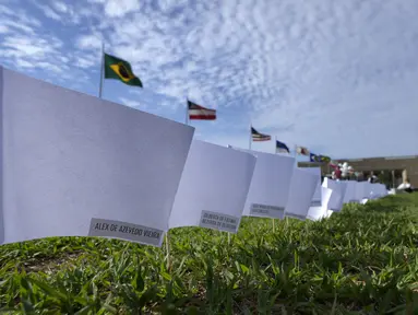 Nama-nama yang meninggal karena COVID-19 menutupi bendera putih sebagai bagian dari protes kebijakan kesehatan pemerintah di luar Kongres Nasional, Brasilia, Jumat (15/10/2021). Sebanyak 600 bendera, masing-masing dengan nama seseorang, mewakili 600.000 total korban meninggal (AP Photo/Eraldo Peres)