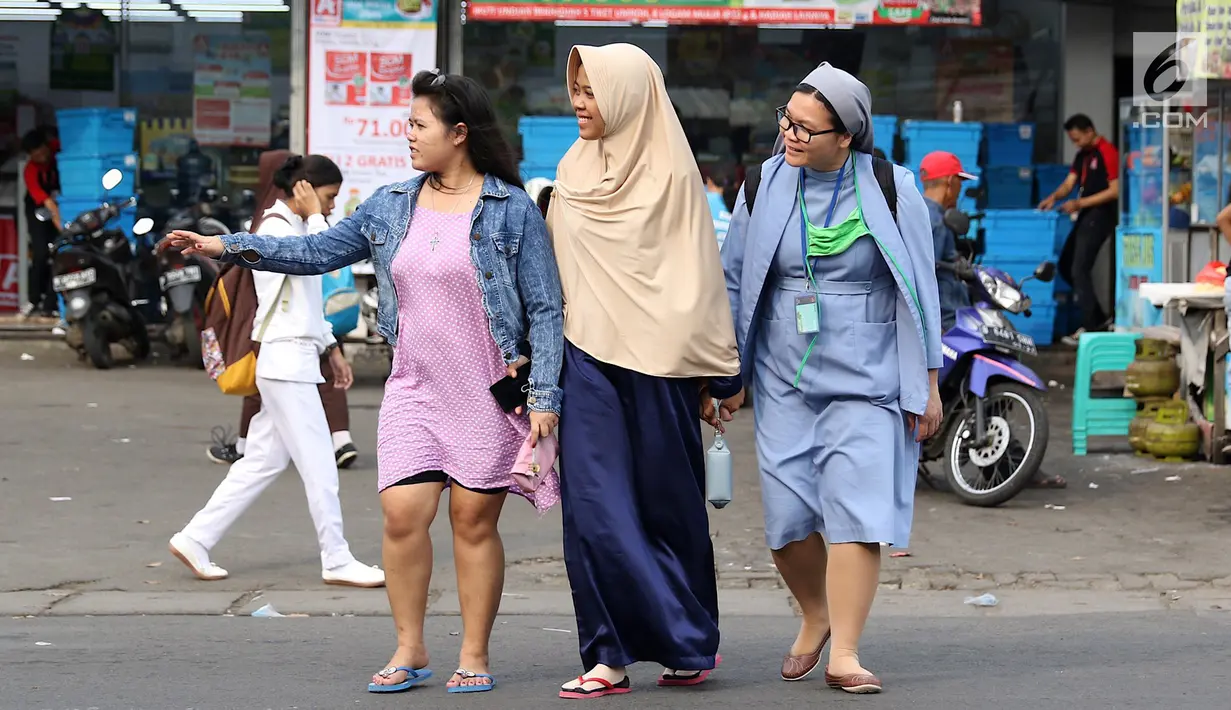 Seorang biarawati bergandeng tangan dengan wanita berkerudung saat menyeberangi jalan di kawasan Lenteng Agung, Jakarta, Rabu (18/4). Keharmonisan keduanya dapat menjadi contoh bagi masyarakat dalam menjaga kedamaian. (Liputan6.com/Immanuel Antonius)