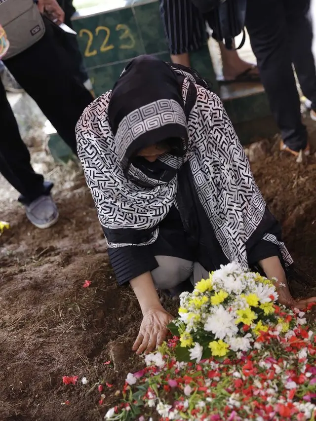 Sang Ibunda tertunduk sedih di atas makam Cecep Reza yang sudah tertutup tanah.