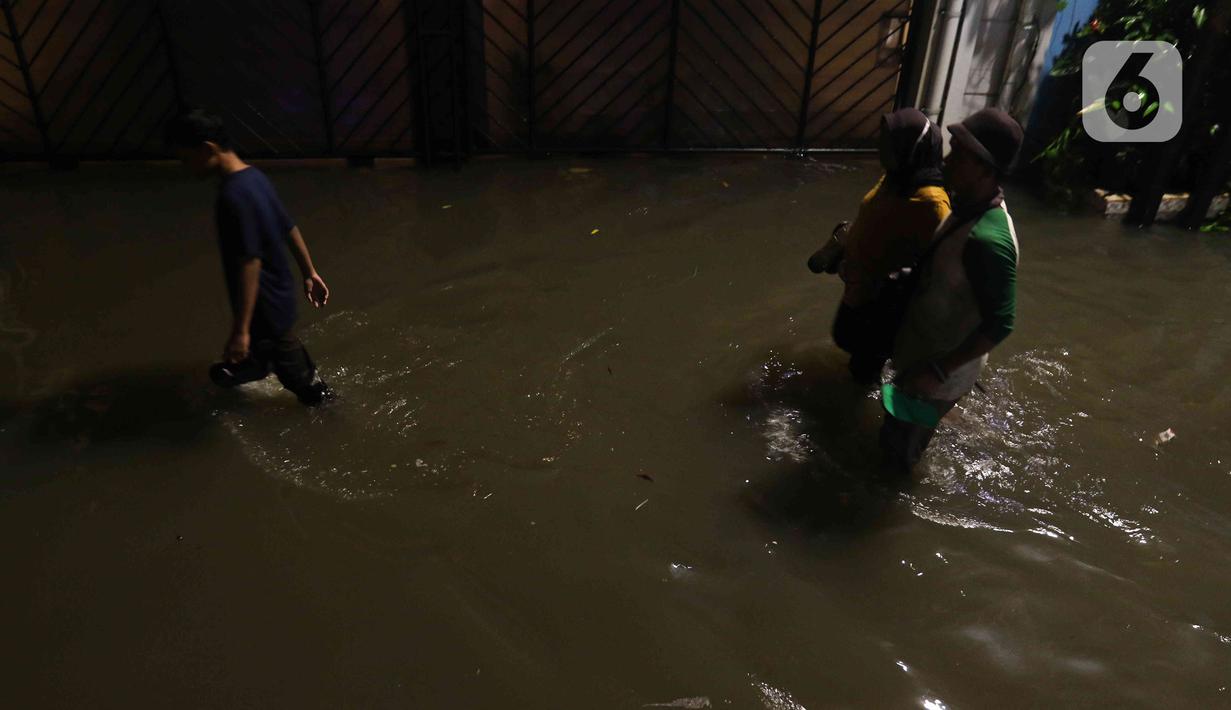 Warga sedang berjalan di tengah banjir yang melanda Jalan Bangka, Jakarta, Rabu (4/1/2023). Hujan deras yang terjadi pada Rabu sore membuat Kali Mampang meluap hingga menyebabkan banjir di kawasan tersebut dengan ketinggian bervariasi mulai dari 40 hingga 60 cm. (Liputan6.com/Herman Zakharia)