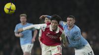Gelandang Manchester City, Phil Foden berebut bola dengan bek Arsenal, Takehiro Tomiyasu selama pertandingan lanjutan Liga Inggris di stadion Emirates di London, Inggris, Kamis (16/2/2023). Hasil ini membuat Man City menggeser Arsenal di puncak klasemen. (AP Photo/Kin Cheung )