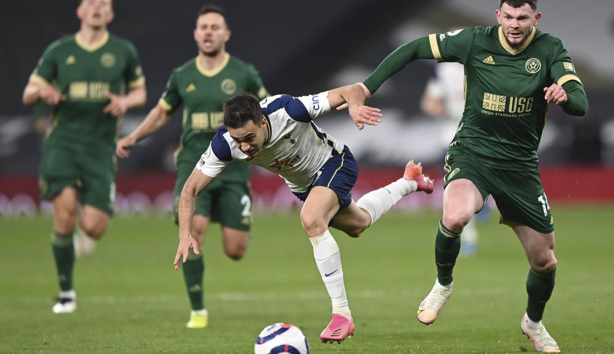Pemain Tottenham Hotspur, Sergio Reguilon, berebut bola dengan pemain Sheffield United, Oliver Burke, pada laga Liga Inggris di London, Minggu (2/5/2021). Tottenham menang dengan skor 4-0. (Shaun Botterill/Pool via AP)