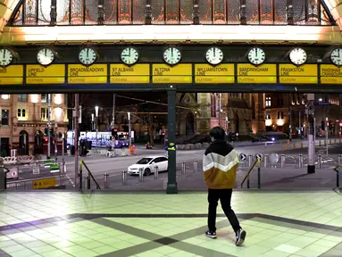 Seorang pria berjalan keluar dari stasiun flinders street selama aturan jam malam di Melbourne, pada Selasa (17/8/2021). Kota terbesar kedua di Australia itu memberlakukan pembatasan tinggal di rumah pada pukul 9 malam hingga 5 pagi untuK meredam lonjakan Covid-19 varian Delta. (William WEST/AFP)
