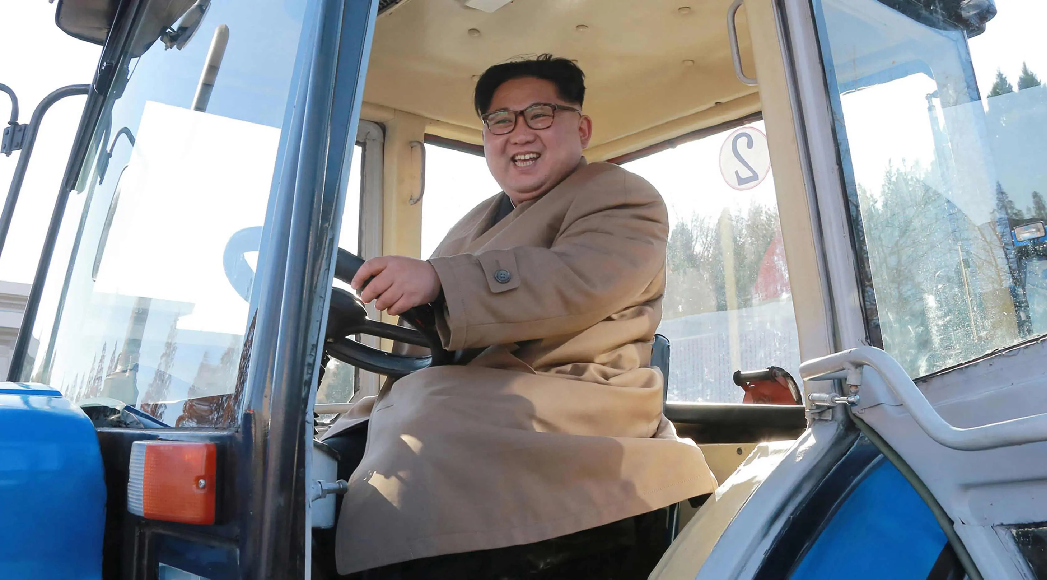 Kim Jong-un saat mengendarai traktor di Kumsong Tractor Factory dalam foto tak bertanggal yang dirilis kantor berita KCNA, (15/11). Traktor buatan dalam negeri ini wujud kemandirian Korut di tengah sanksi internasional. (AFP Photo/Kcna Via Kns/Str)