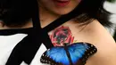 Seorang pengunjung yang merupakan wartawan TV Jepang tersenyum saat mengetahui kupu-kupu hinggap di tato bunga tubuhnya pada pameran Sensasional Butterflies di Museum Sejarah Alam,London, Inggris 23 Maret 2016. (REUTERS / Dylan Martinez)