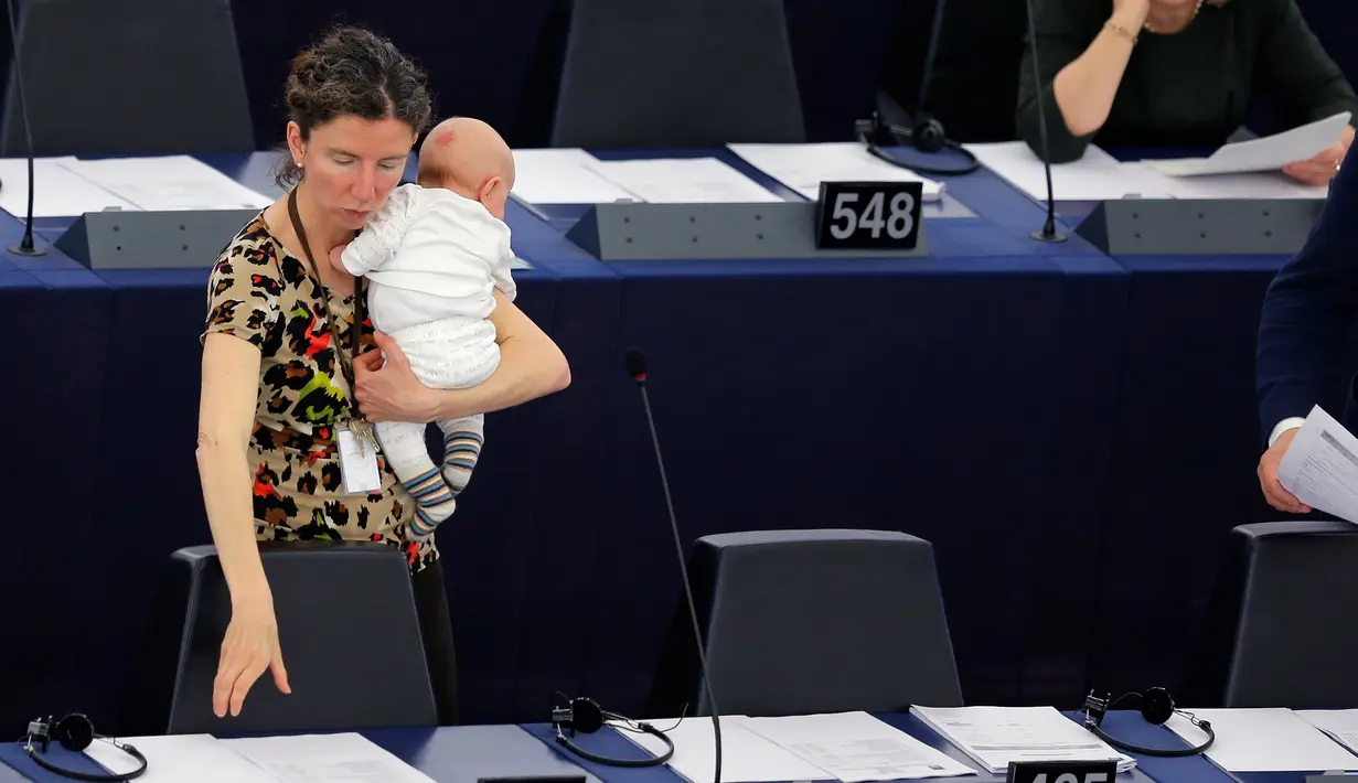 Anggota Parlemen Eropa Anneliese Dodds saat mencoba mendiamkan anaknya yang diajak rapat di kantor Parlemen Eropa, Strasbourg , Perancis , 14 April 2016. Wanita ini tampak santai menikmati rapat sambil mengasuh anaknya.  (REUTERS / Vincent Kessler)