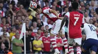 Bek Arsenal, Takehiro Tomiyasu (kiri) melompat untuk sundulan saat melawan Tottenham Hotspur pada pertandingan lanjutan Liga Inggris di stadion Emirates di London, Minggu (27/9/2021). Arsenal menang atas Tottenham dengan skor 3-1. (AP Photo/Frank Augstein)