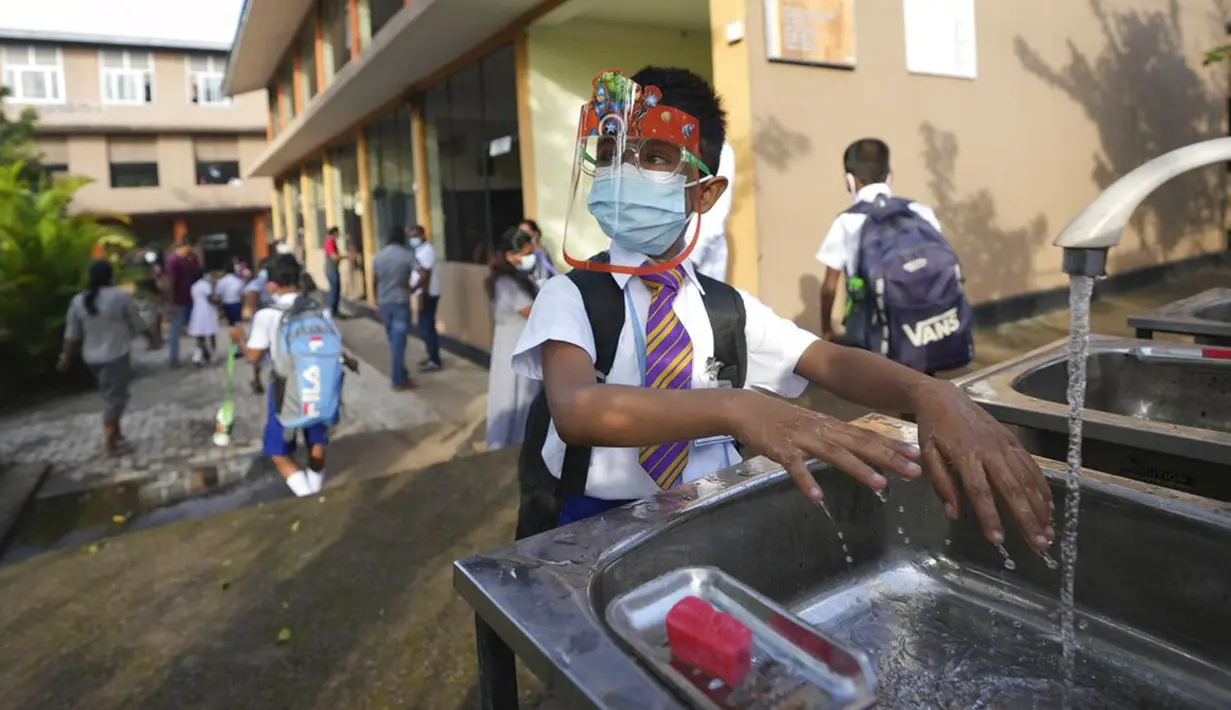 Seorang siswa sekolah dasar mencuci tangan sebelum memasuki ruang kelas di sebuah sekolah di Kolombo, Sri Lanka, 25 Oktober 2021. Sri Lanka memulai kembali semua sekolah dasar yang telah ditutup lebih dari enam bulan karena pandemi COVID-19. (AP Photo/Eranga Jayawardena)