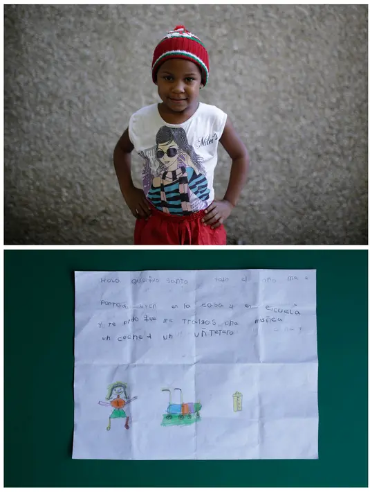 Yoselin Ortuno (5 Th), berpose usai menggambar tentang hadiah apa yang dia ingin saat Natal dari Santa di Caracas, Venezuela 5 Desember 2016. Yoselin ingin boneka, kereta dorong dan botol. (REUTERS / Marco Bello)