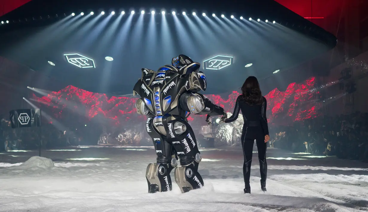 Model Irina Shayk melenggang ditemani robot sambil membawakan koleksi desainer Philipp Plein dalam New York Fashion Week 2018, Sabtu (10/2). Robot warna hitam yang bentuknya menyerupai Transformers itu lalu berjalan di sepanjang catwalk  (AP/Craig Ruttle)