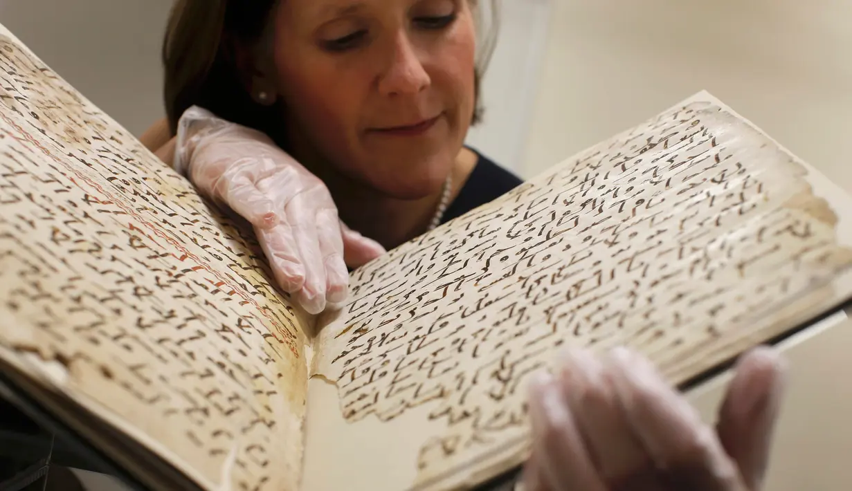 Konservator, Marie Sviergula memperlihatkan penggalan naskah Al-Quran tertua di dunia di Universitas Birmingham, Inggris, Rabu (22/7/2015). Penanggalan radiokarbon menunjukkan manuskrip itu berusia setidaknya 1.370 tahun. (REUTERS/Peter Nicholls)