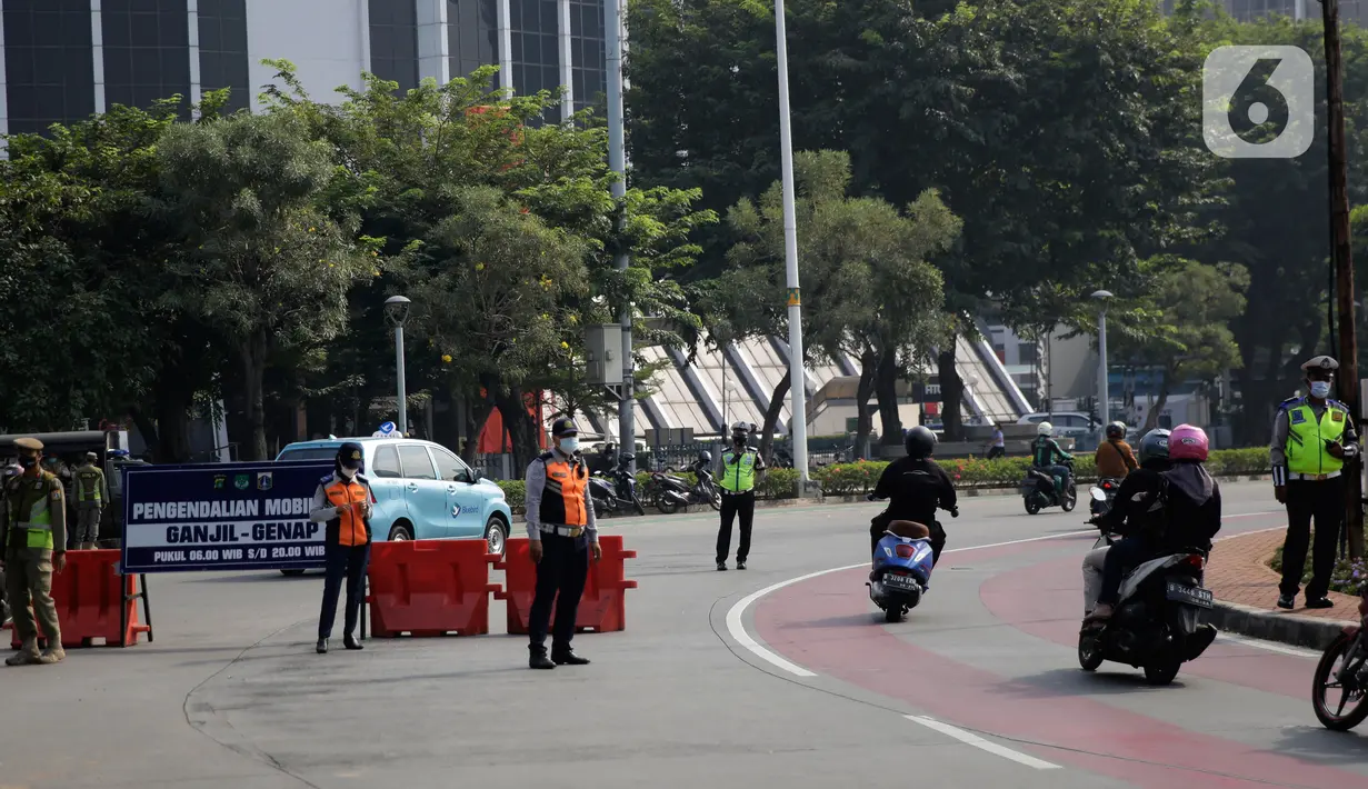 Petugas mengawasi kendaraan yang melintas di pos penyekatan ganjil-genap di Bundaran Senayan, Minggu (5/9/2021). Pembatasan kendaraan dengan sistem pelat nomor kendaraan ini tetap berlaku di akhir pekan, Sabtu dan Minggu. (Liputan6.com/Angga Yuniar)